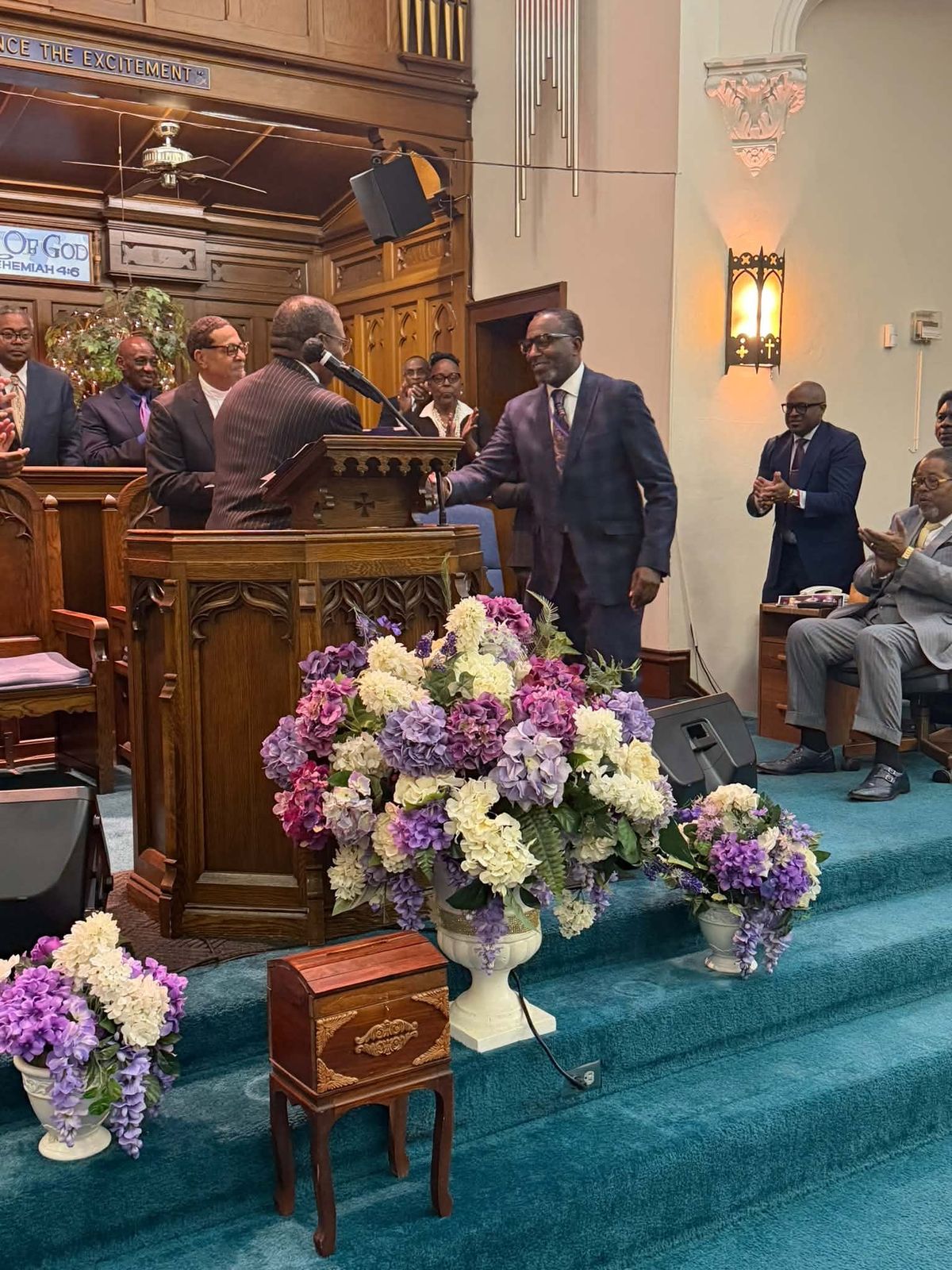 Pastor Hughes shaking hands at the pulpit as ministers applaud